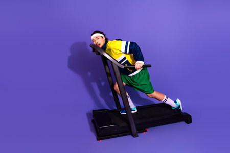 Young athlete with retro style on treadmill against purple background focusing on active lifestyle...