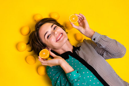 Photo of charming lovely cheerful woman wear stylish clothes hold two lemons isolated on yellow color backgroundの写真素材