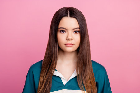 Portrait of a young lovely adult woman in casual green wear against a pink color backgroundの写真素材