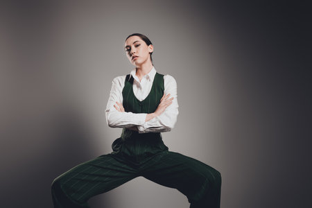 Gorgeous Confident Businesswoman in Green Suit with Crossed Arms on Gradient Grey Backgroundの写真素材