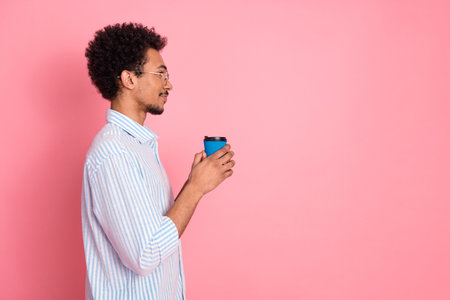 Young man with coffee cup on bright pink background, cheerful and relaxed expression, modern and...