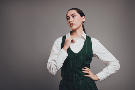 Stunning Young Businesswoman Posing in Green Formal Vest Against a Neutral Backgroundの写真素材