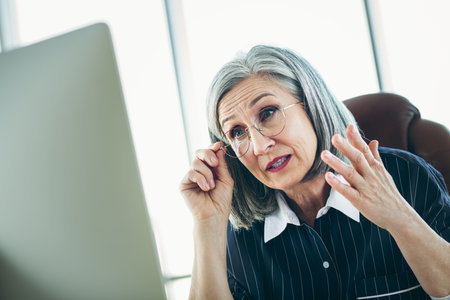 Mature Businesswoman in Office Setting Expressing Concern During Work Discussion, Demonstrating...