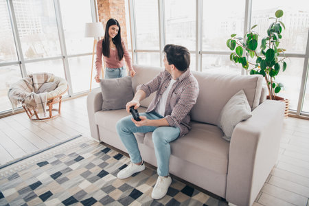 Casual young couple enjoying leisure time in modern living room during a sunny day, showcasing love,...