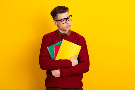 Young Male Student Posing Confidently in Stylish Sweater Against a Yellow Backgroundの写真素材
