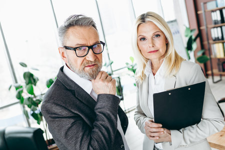 Professional Business Colleagues Discussing Workplace Strategies in a Bright Office Settingの写真素材