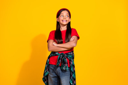 Confident young girl in casual outfit striking a pose against yellow background, showcasing vibrant style and youthfulness.の写真素材
