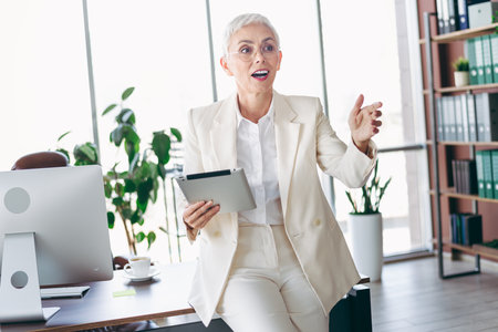 Confident Senior Businesswoman Sharing Insights in a Modern Office Environmentの写真素材