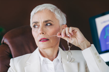 Confident mature businesswoman in formalwear at the workplace, looking thoughtful and poised with a strategic mindsetの写真素材