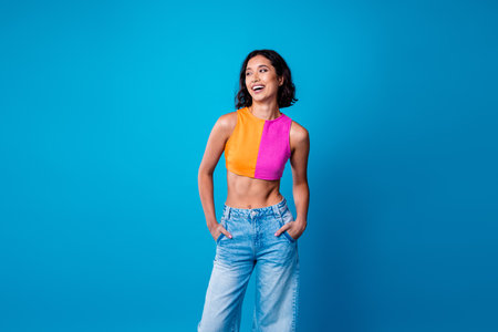 Joyful young woman posing in stylish casual summer outfit against vibrant blue backgroundの写真素材