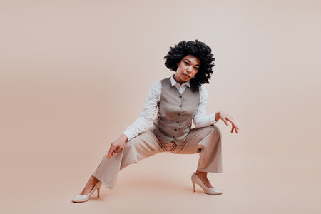 Confident Businesswoman in Elegant Formalwear Posing Against a Neutral Beige Background, Exemplifying Modern Professional Styleの写真素材