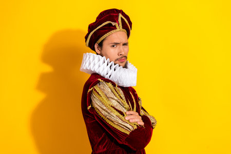 Young man in vintage aristocratic costume posing against a bright yellow background showcasing historical fashionの写真素材