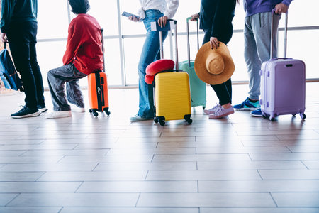 Group of young travelers with colorful luggage waiting in line at an airport terminal ready for their adventureの写真素材