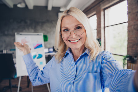 Confident senior businesswoman presenting ideas in a bright modern officeの写真素材