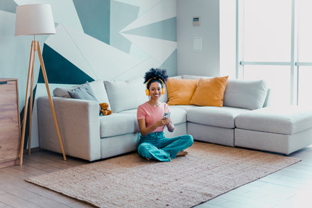 Young woman enjoying leisure time at home sitting on floor in bright living room interior with modern designの写真素材