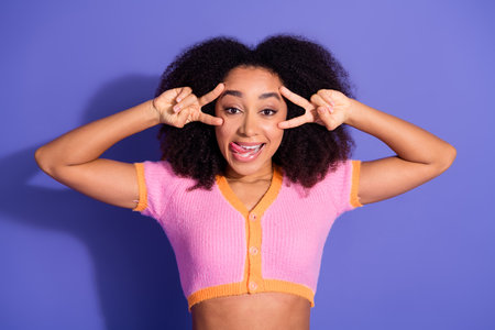 Playful young woman posing with cheerful gestures on a purple background, showcasing fun and vibrant...