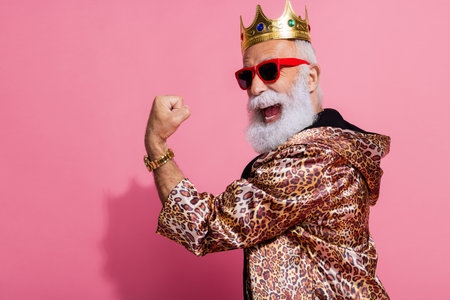 Photo of attractive grandpa winning raise fist dressed stylish leopard print garment isolated on pink color backgroundの写真素材