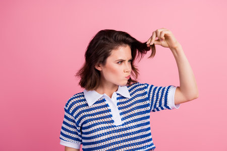 Stylish brunette woman in casual knitwear top posing playfully against a vibrant pink backgroundの写真素材