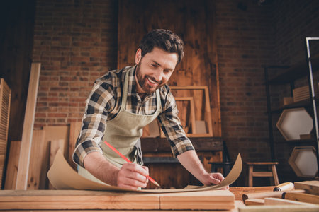 Photo of happy smiling professional builder guy hold write blueprint plan in garage indoorsの写真素材