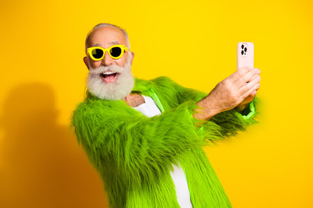 Elderly man in vibrant outfit smiling and taking selfie against a bright background