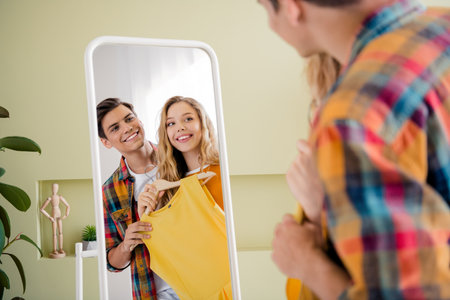 Photo of cute positive people sweet couple choosing outfits for evening romantic night date indoors home roomの写真素材