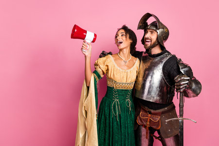 Playful couple in medieval costumes posing against a pink backdropの写真素材
