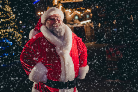Photo of positive joyful funky retired old man santa claus wear red coat stand own house home lapland village residence outdoorsの写真素材