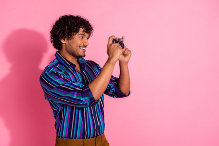 Portrait of nice young man shooting empty space wear shirt isolated on pink color backgroundの写真素材