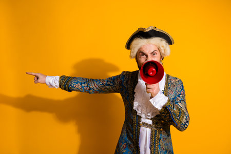 Dramatic portrayal of an aristocrat with a megaphone against vibrant yellow backdropの写真素材