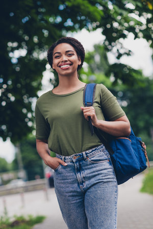 Smiling young woman enjoying a sunny day walk with backpack in urban settingの写真素材