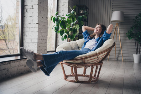 Young woman enjoying relaxation in a cozy living room with natural lightingの写真素材