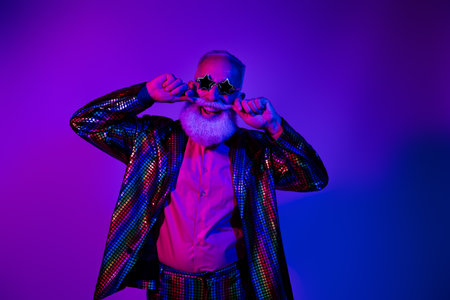 Photo of funky cool mature guy dressed glamour costume star eyewear dancing disco touch beard isolated neon purple color backgroundの写真素材