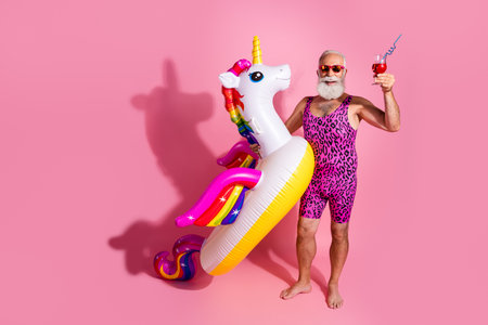 Photo of cheerful positive man wear swimwear enjoy relax rest vacation resort inflatable toy isolated on pink color backgroundの写真素材