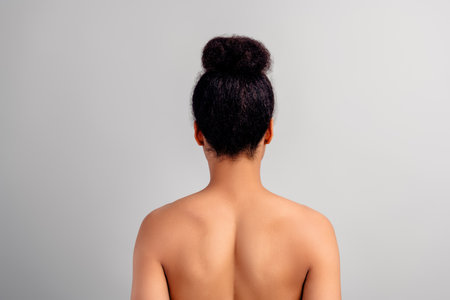 Rear view of a young woman with natural hairstyle and flawless skin against a white backgroundの写真素材