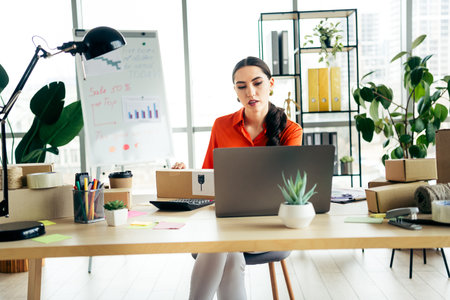 Young entrepreneur working in a modern workspace processing online orders while managing ecommerce and logisticsの写真素材