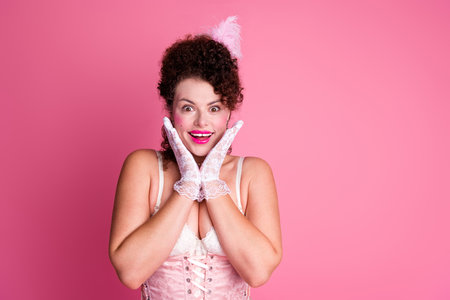 A young woman in costume poses against a bright pink background, embodying a blend of historical...