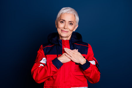 Photo of nice senior woman touch chest heart health wear uniform paramedic doctor help isolated on dark blue color backgroundの写真素材