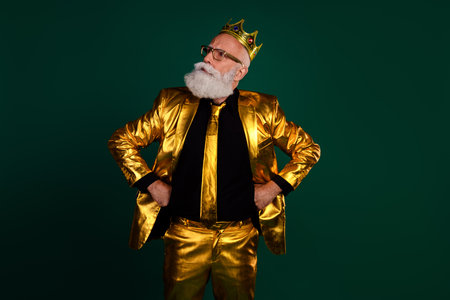 Charismatic elderly man in glowing golden suit, wearing a crown, showcases his elegance in a vibrant retro style against a green backdrop.の写真素材