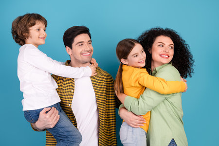 Happy family with parents and children bonding together in casual clothing against a blue background, showcasing love and joyful emotions.の写真素材