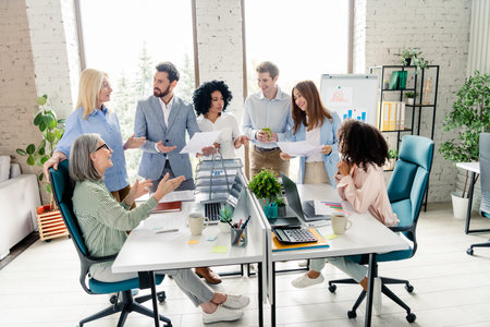 Group of professionals collaborating in modern office workspace during daylight hours with a...