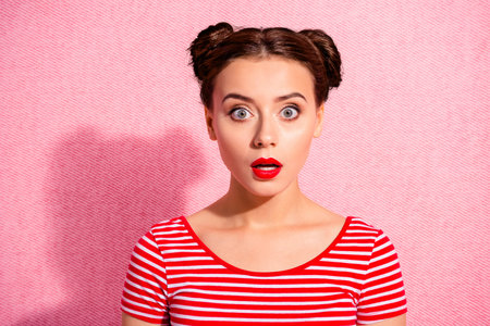 Close up photo beautiful she her lady pretty two buns unexpected news big eyes opened mouth speechless oh no face bright pomade lipstick wear casual striped red white t-shirt isolated pink backgroundの写真素材