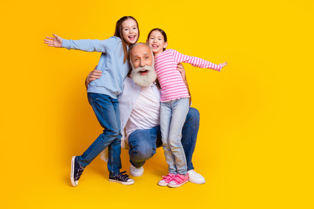 Grandfather Enjoying Happy Moments With Two Granddaughters Against Vibrant Yellow Background
