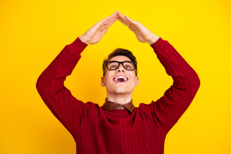 Young Man Making Creative Hand Gesture While Smiling Against Yellow Backgroundの写真素材