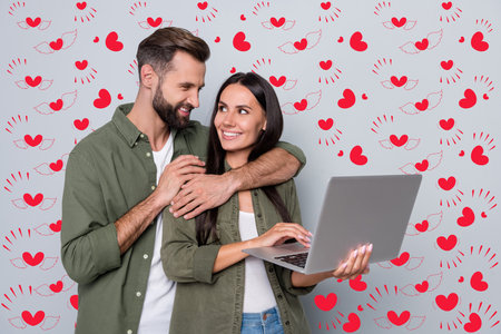 Portrait of attractive tender cheerful couple cuddling using laptop searching web isolated over grey pastel color backgroundの写真素材