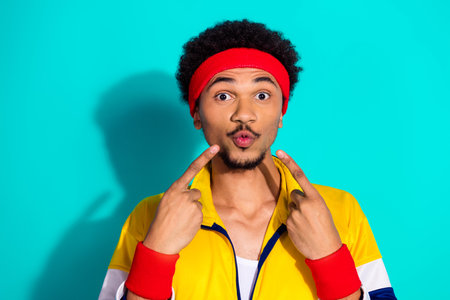 Young male athlete in vibrant activewear pointing happily, expressing joy and energy amidst a retro...