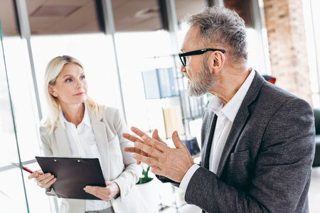 Business professionals engaged in discussion during an office meeting, emphasizing teamwork and collaboration in a formal workspace.の写真素材