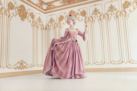 Elegant woman in luxurious pink gown poses in ornate room, embodying a blend of historical and...