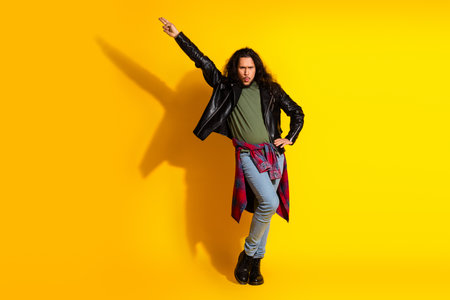 Fashionable young man with expressive pose on vibrant yellow background showcasing modern style and...