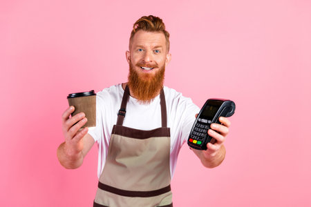 Friendly barista serving coffee and demonstrating a payment terminal against a pink background