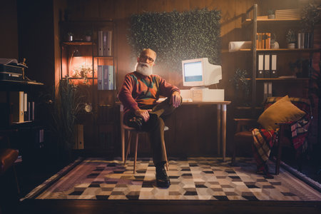 Mature professional man with retro computer in cozy home office interior featuring greenery and warm...